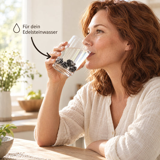 Glas Wasser mit Schneeflockenobsidian Wassersteinen