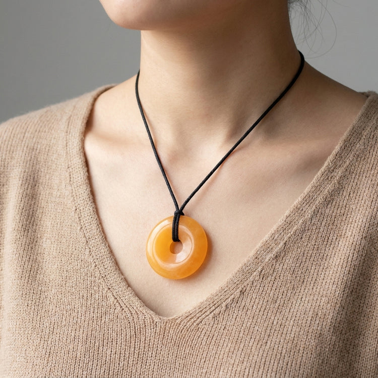 Orangencalcit Donut | 40 mm Anhänger + Baumwollband — Lifestyle-Tragebild