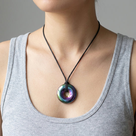 Regenbogen Hämatit Donut | 30 mm Anhänger + Baumwollband — Lifestyle-Tragebild