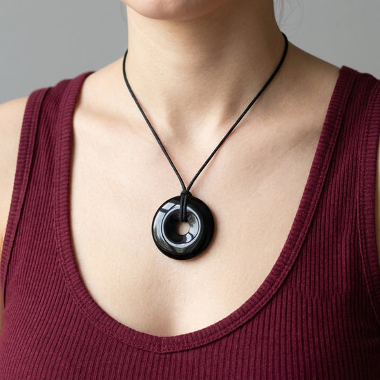 Obsidian, schwarz Donut | 40 mm Anhänger + Baumwollband — Lifestyle-Tragebild